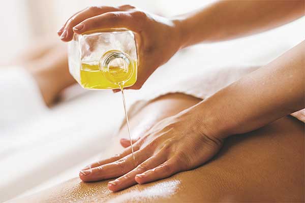 aromatherapy oil being poured onto a woman’s back