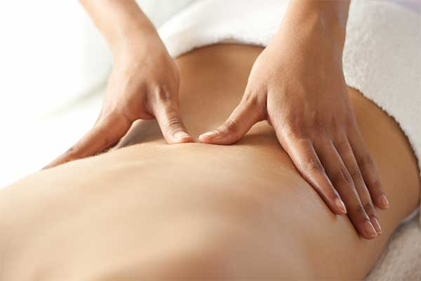therapist applying massage techniques to a woman's back