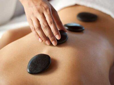 therapist placing a basalt stone on a woman's back, during a hot stone massage